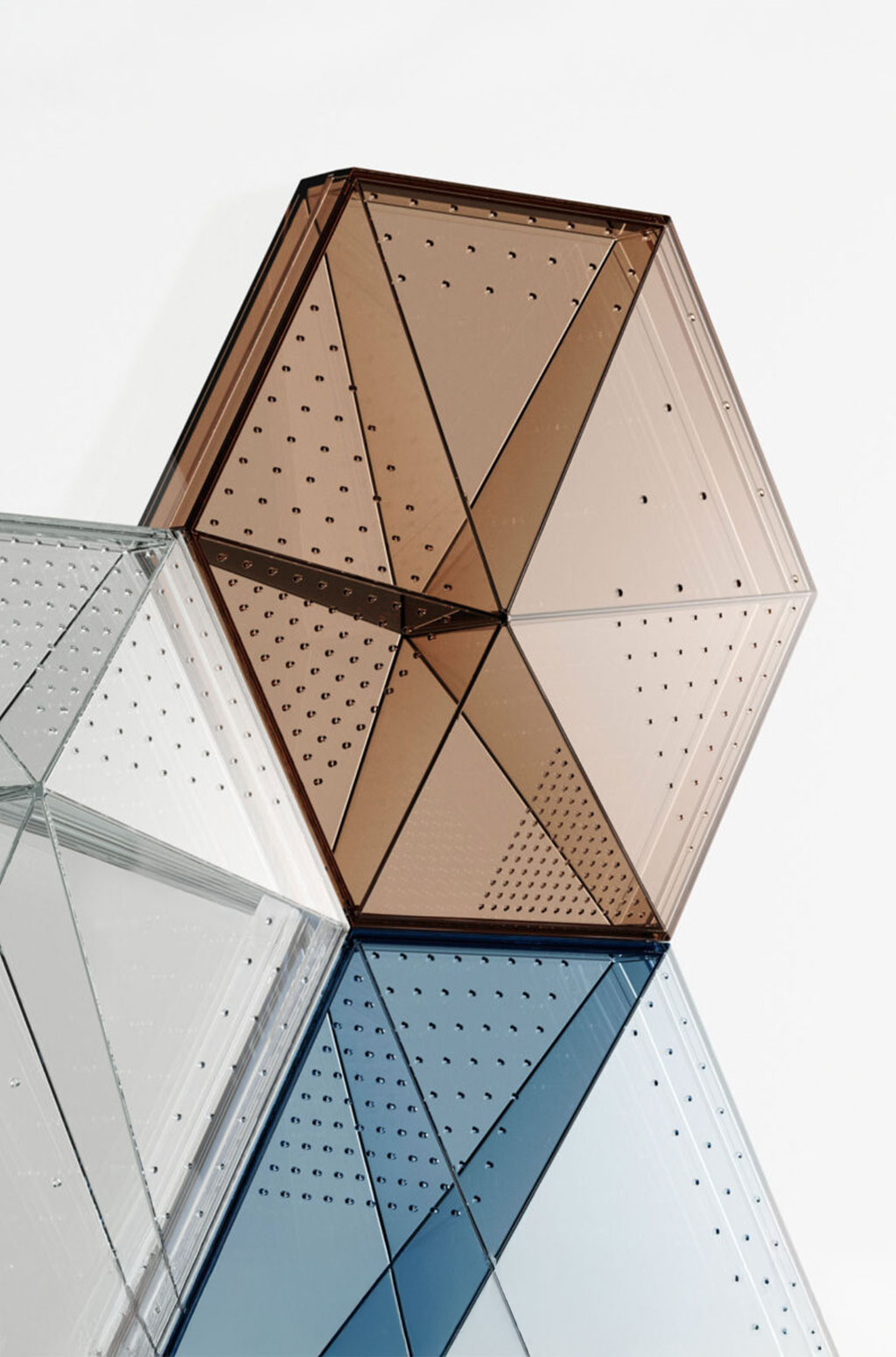 Hexagonal-shaped transparent panel with small perforations across its symmetrical surface, available in shades of brown, clear, and blue, emphasizing a sleek and minimalist design