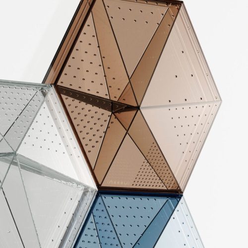 Hexagonal-shaped transparent panel with small perforations across its symmetrical surface, available in shades of brown, clear, and blue, emphasizing a sleek and minimalist design